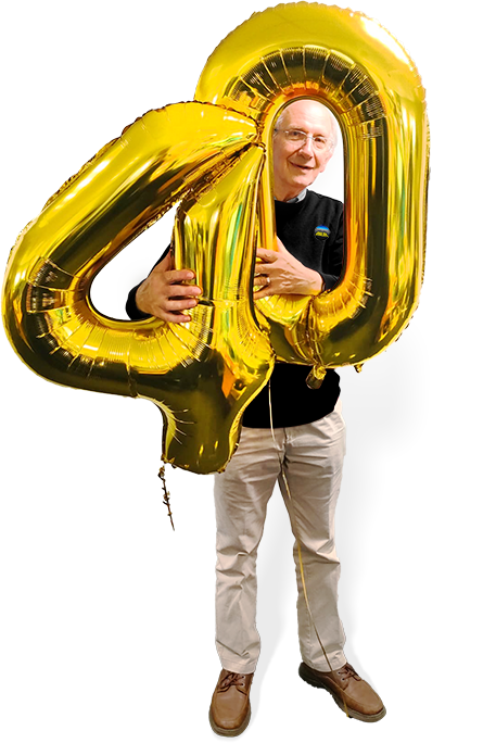 Peter Evans proudly holds 40th balloons marking four decades of TMS Excellence.